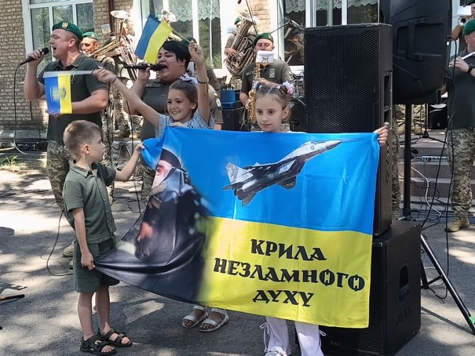 Прапор із зображенням батька тримають діти Євгена Лисенка Єгор і Ліза, а прапорцями вимахує співуче сонечко з Санжарихи Софія Романюк